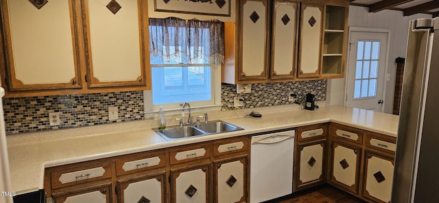 kitchen with tasteful backsplash, open shelves, light countertops, white dishwasher, and a sink