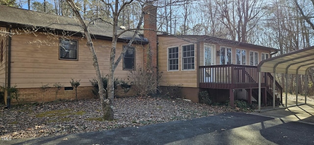 view of side of home featuring crawl space, a carport, and driveway