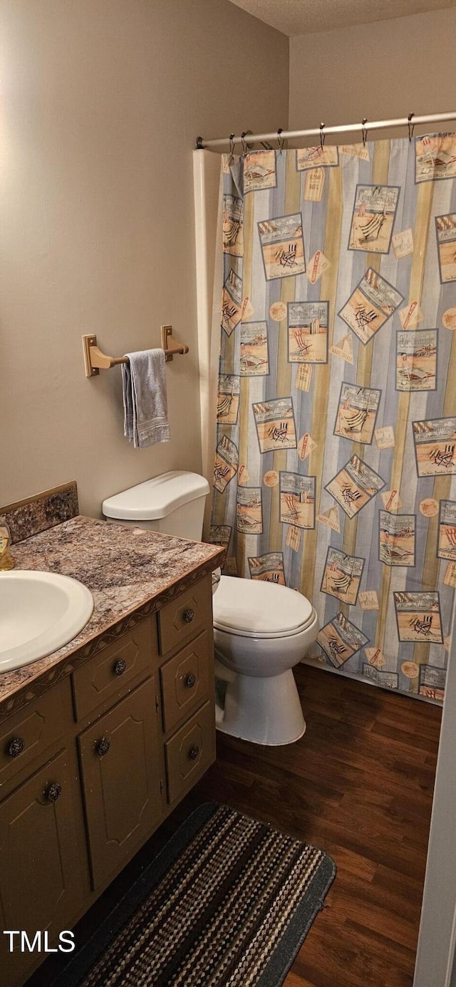 full bathroom featuring a shower with shower curtain, toilet, wood finished floors, and vanity