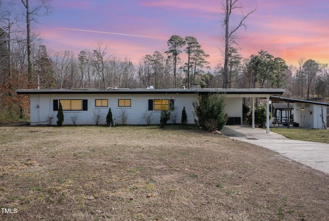 mid-century modern home featuring an attached carport, a lawn, and concrete driveway