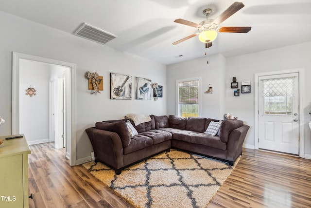 living area featuring a ceiling fan, wood finished floors, visible vents, and baseboards