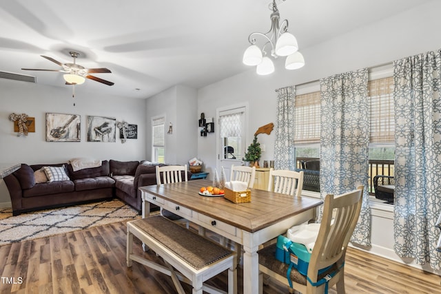 dining area featuring ceiling fan with notable chandelier, wood finished floors, and visible vents