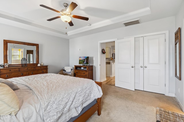 bedroom featuring visible vents, a tray ceiling, a closet, baseboards, and light colored carpet