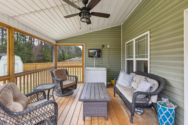 deck featuring a ceiling fan, fence, a shed, an outdoor structure, and an outdoor hangout area