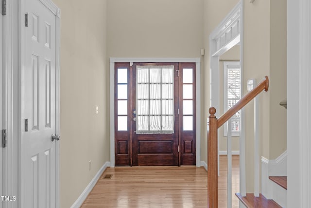 foyer entrance with stairs, visible vents, baseboards, and light wood finished floors