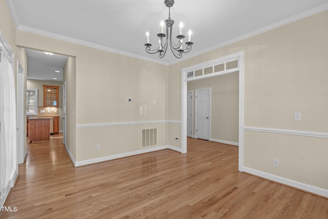 unfurnished dining area with visible vents, baseboards, an inviting chandelier, light wood-style floors, and crown molding