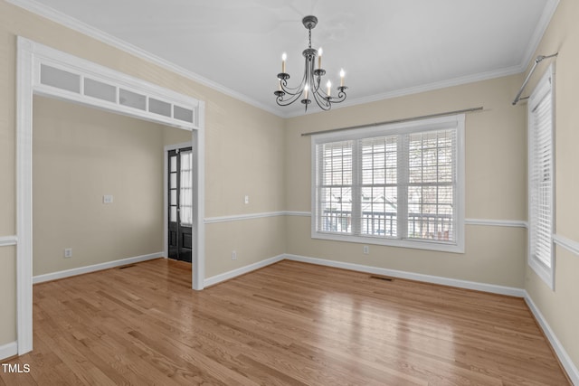 unfurnished room featuring crown molding, wood finished floors, baseboards, and a chandelier