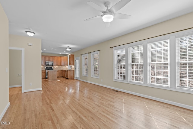 unfurnished living room with a healthy amount of sunlight, light wood-type flooring, and baseboards