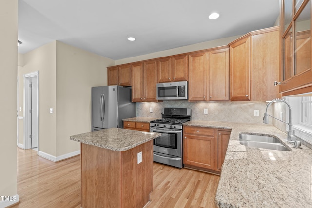 kitchen with a sink, appliances with stainless steel finishes, light wood-type flooring, backsplash, and a center island