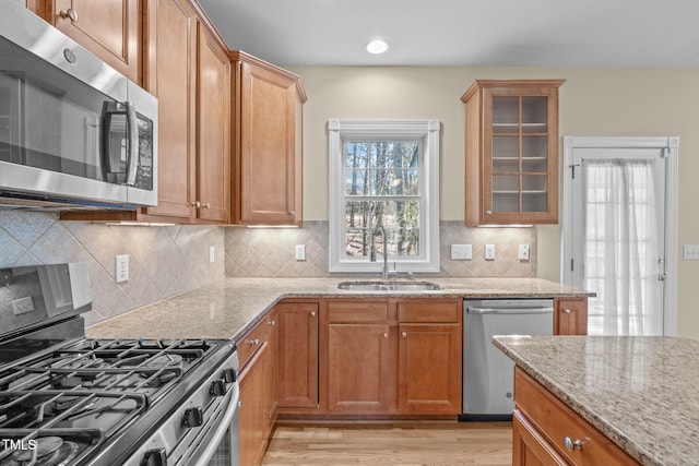 kitchen featuring plenty of natural light, light stone countertops, appliances with stainless steel finishes, and a sink