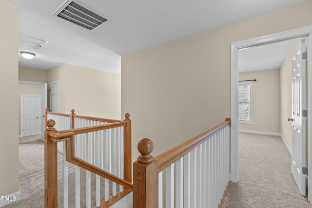 hall featuring baseboards, an upstairs landing, visible vents, and light carpet