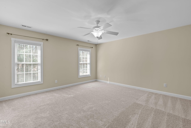 carpeted spare room featuring visible vents, ceiling fan, and baseboards