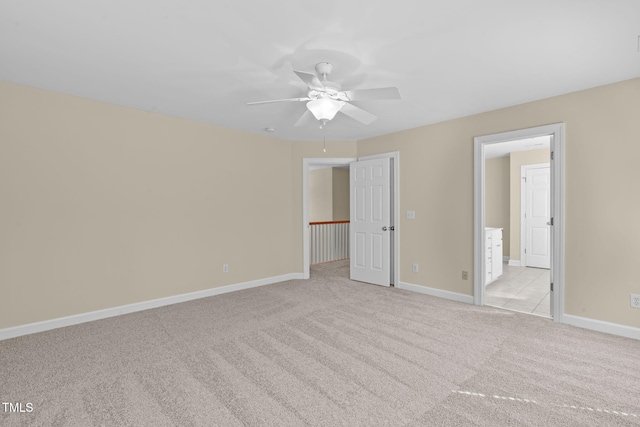 unfurnished bedroom with baseboards, light carpet, connected bathroom, and a ceiling fan