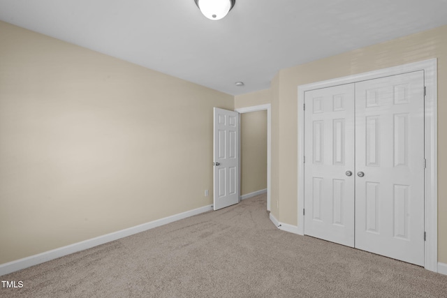 unfurnished bedroom with baseboards, carpet floors, and a closet