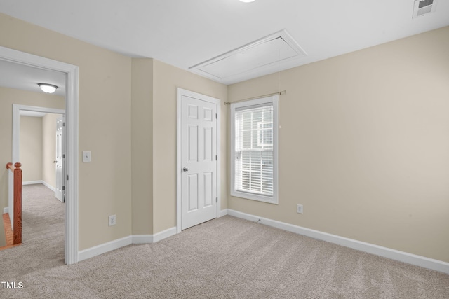 unfurnished bedroom with baseboards, visible vents, attic access, and carpet