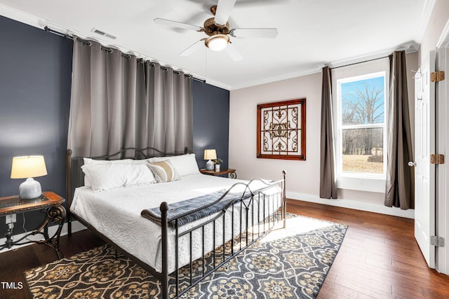 bedroom with visible vents, baseboards, ornamental molding, wood finished floors, and a ceiling fan