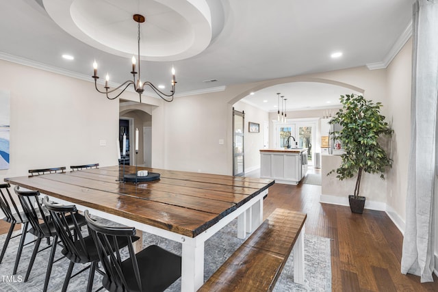 dining area with baseboards, arched walkways, dark wood-type flooring, and ornamental molding