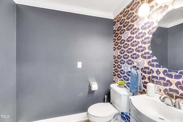 half bath featuring baseboards, wallpapered walls, a sink, crown molding, and toilet