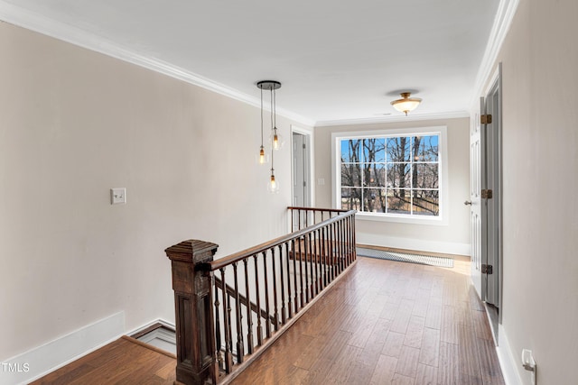 hallway featuring wood finished floors, an upstairs landing, baseboards, and ornamental molding