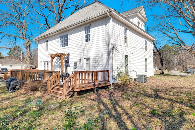 rear view of house with a wooden deck, central AC unit, a pergola, and roof with shingles