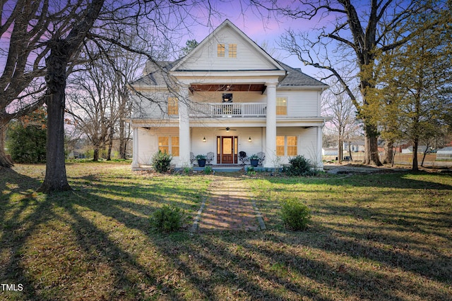 neoclassical / greek revival house with a balcony, a porch, ceiling fan, and a front yard