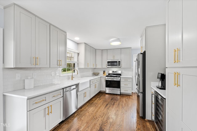 kitchen with dark wood-style flooring, a sink, stainless steel appliances, wine cooler, and tasteful backsplash