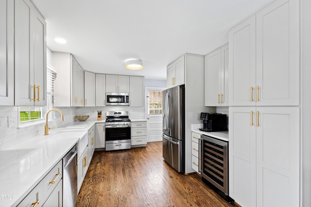 kitchen featuring beverage cooler, dark wood-style floors, appliances with stainless steel finishes, and light countertops