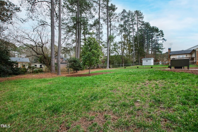 view of yard with an outbuilding, a storage unit, and fence