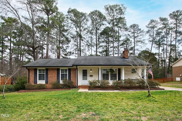 ranch-style house featuring brick siding, a chimney, a front yard, and fence