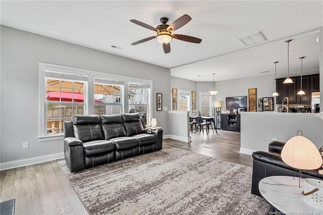 living room featuring visible vents, baseboards, and wood finished floors