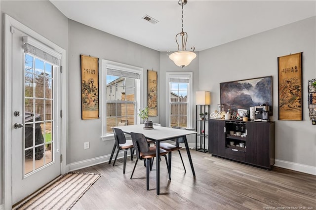 dining room featuring a wealth of natural light, visible vents, baseboards, and wood finished floors