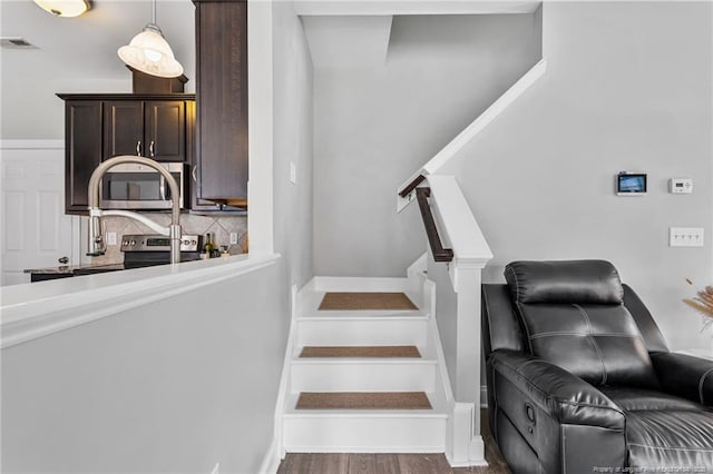 staircase with visible vents, baseboards, and wood finished floors