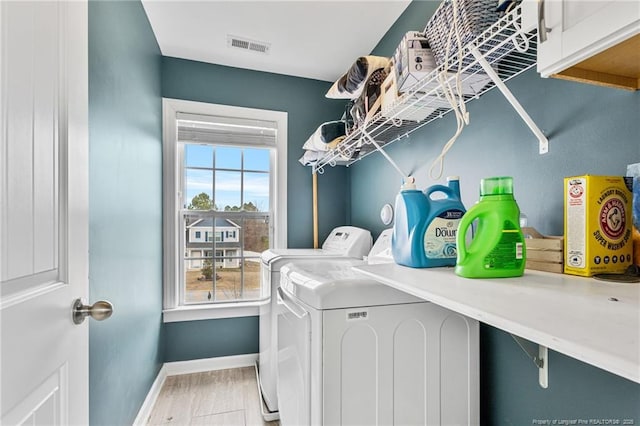 clothes washing area with visible vents, independent washer and dryer, wood finished floors, cabinet space, and baseboards