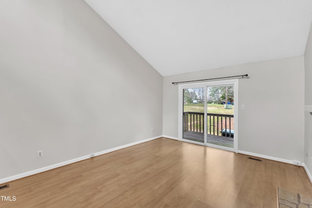 unfurnished room featuring visible vents, lofted ceiling, baseboards, and wood finished floors