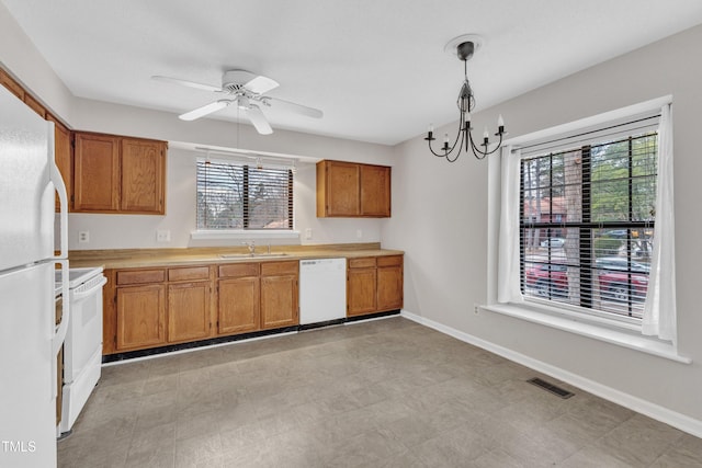 kitchen with visible vents, light countertops, brown cabinets, white appliances, and a sink