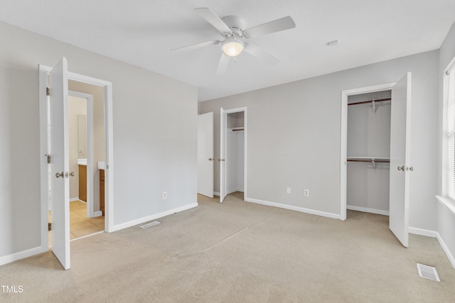 unfurnished bedroom featuring visible vents, two closets, a ceiling fan, carpet flooring, and baseboards