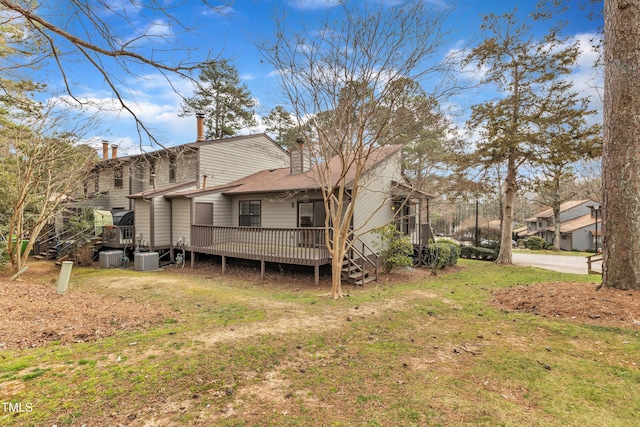 back of property with central air condition unit, a lawn, a deck, and a chimney