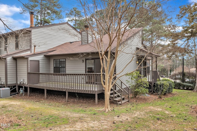 rear view of property featuring central AC, a yard, roof with shingles, a wooden deck, and a chimney