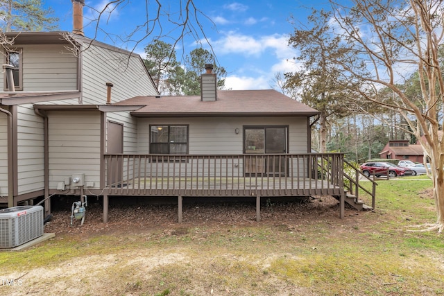 back of house featuring a chimney, a yard, a wooden deck, and central AC