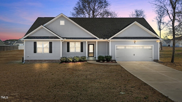 view of front facade featuring driveway, board and batten siding, roof with shingles, a front yard, and a garage