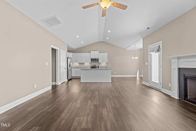 unfurnished living room with a fireplace, ceiling fan with notable chandelier, visible vents, and dark wood-style flooring