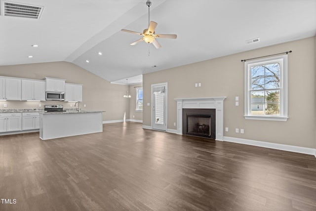 unfurnished living room featuring visible vents, lofted ceiling, dark wood-type flooring, and a ceiling fan