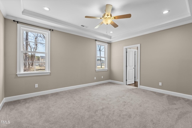 carpeted empty room featuring ceiling fan, a tray ceiling, visible vents, and ornamental molding