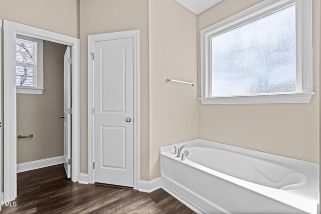 full bathroom with a garden tub, wood finished floors, and baseboards