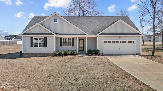 view of front of home featuring driveway, fence, board and batten siding, a shingled roof, and a garage