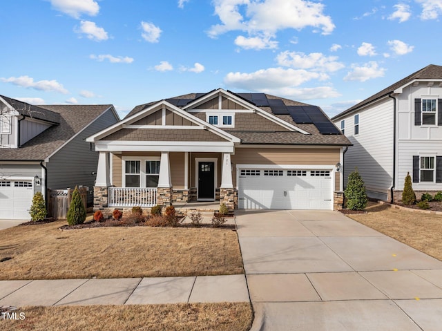 craftsman house with driveway, an attached garage, covered porch, board and batten siding, and roof mounted solar panels