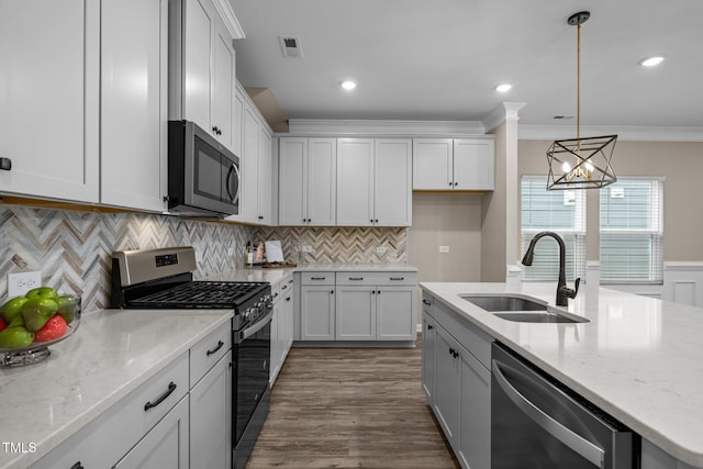 kitchen with light stone countertops, visible vents, a sink, appliances with stainless steel finishes, and crown molding