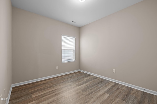 empty room featuring visible vents, baseboards, and wood finished floors