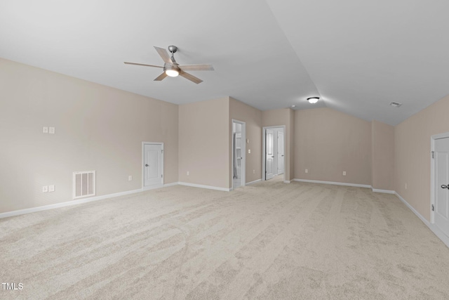 unfurnished room with a ceiling fan, visible vents, baseboards, lofted ceiling, and light colored carpet