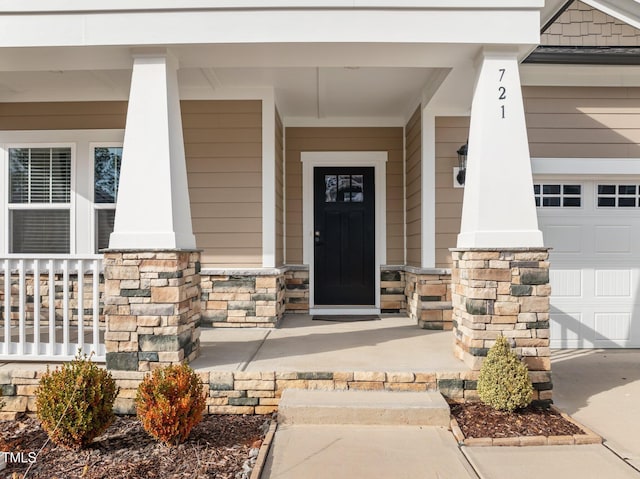 doorway to property with a garage, stone siding, and covered porch